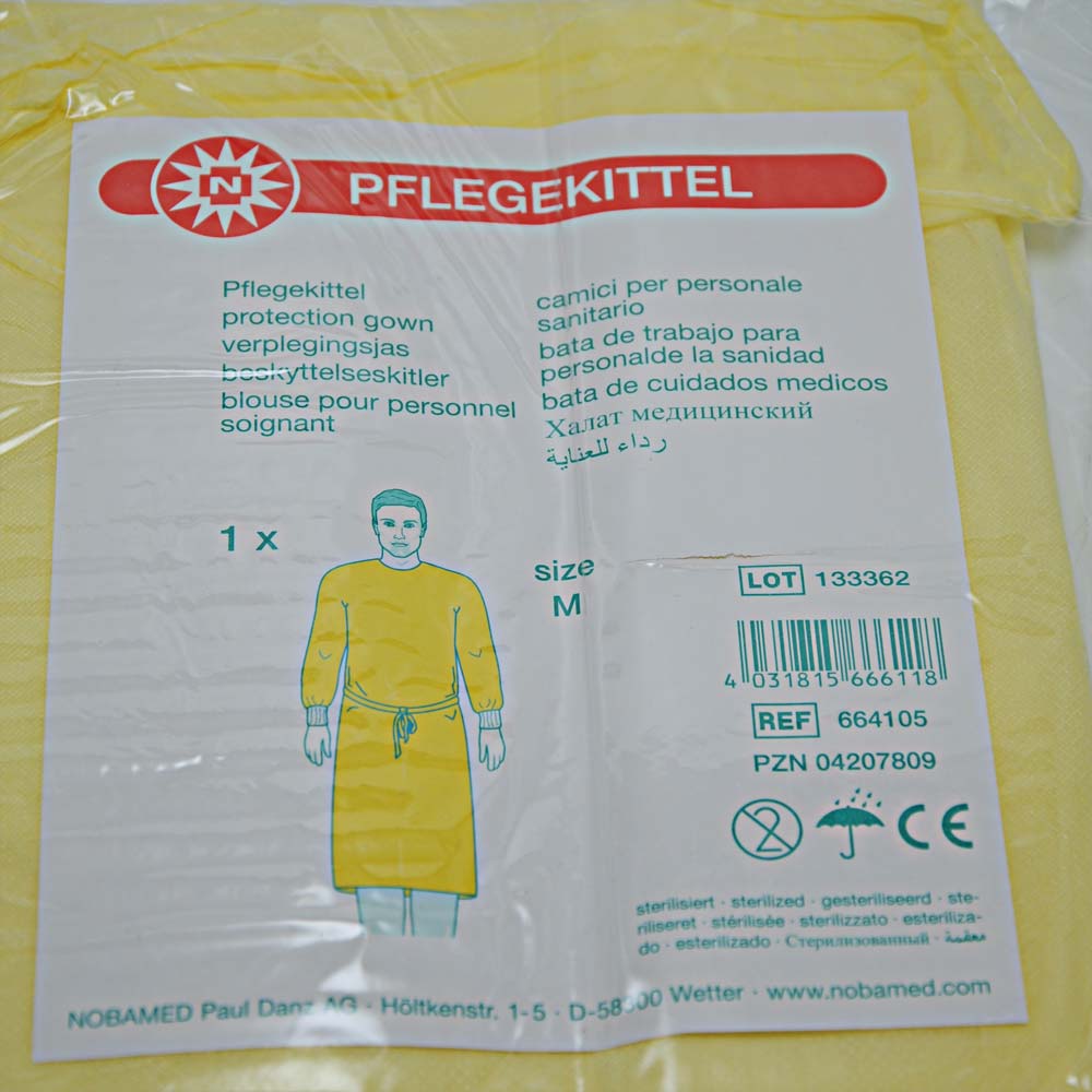 Gelber Pflegekittel aus Vliesstoff, Größe M, Etikett sichtbar
