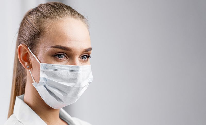Frau mit Maske informiert über Mundschutzpflicht.