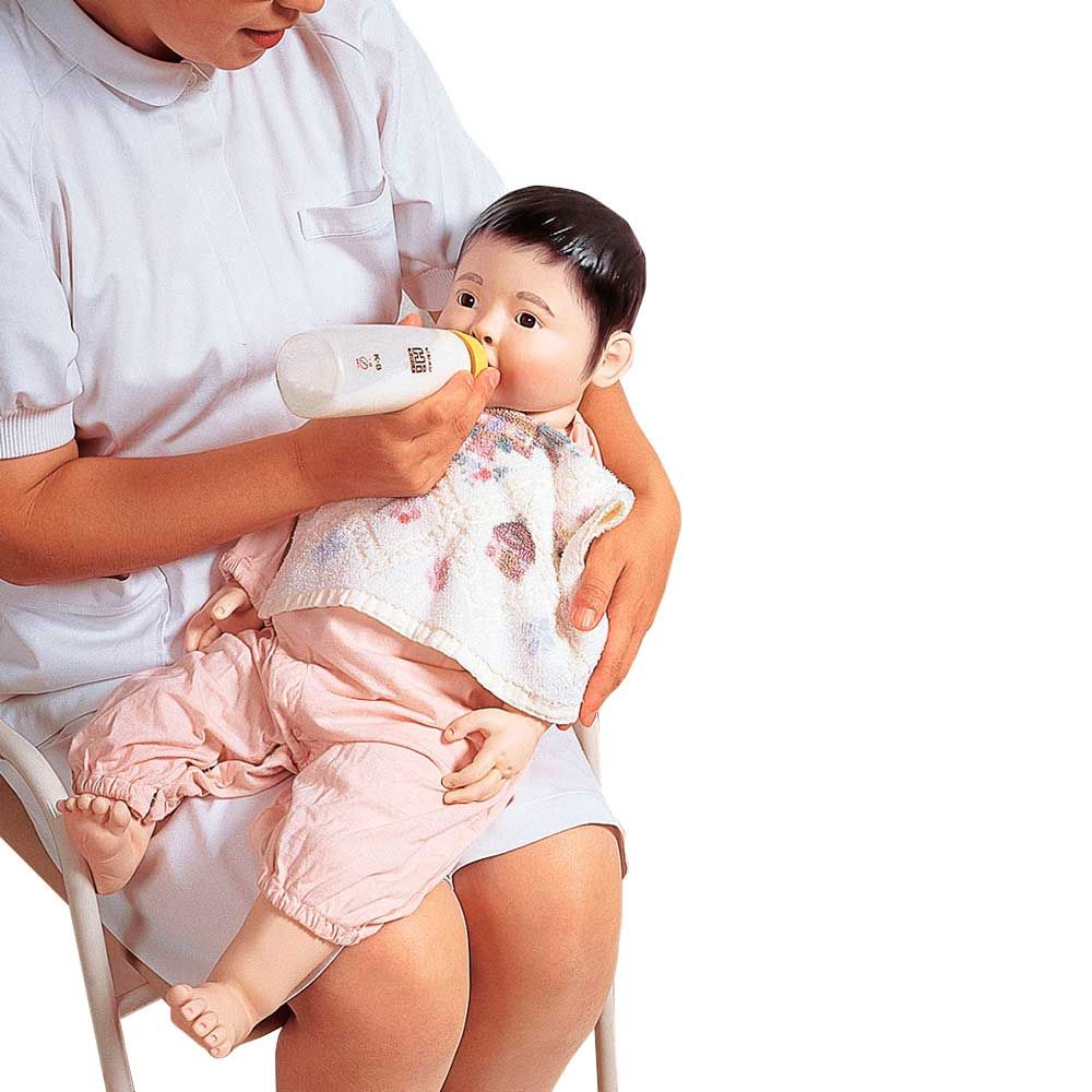 Weibliche Säuglings-Krankenpflegpuppe mit Fläschchen, gehalten von einer Pflegekraft
