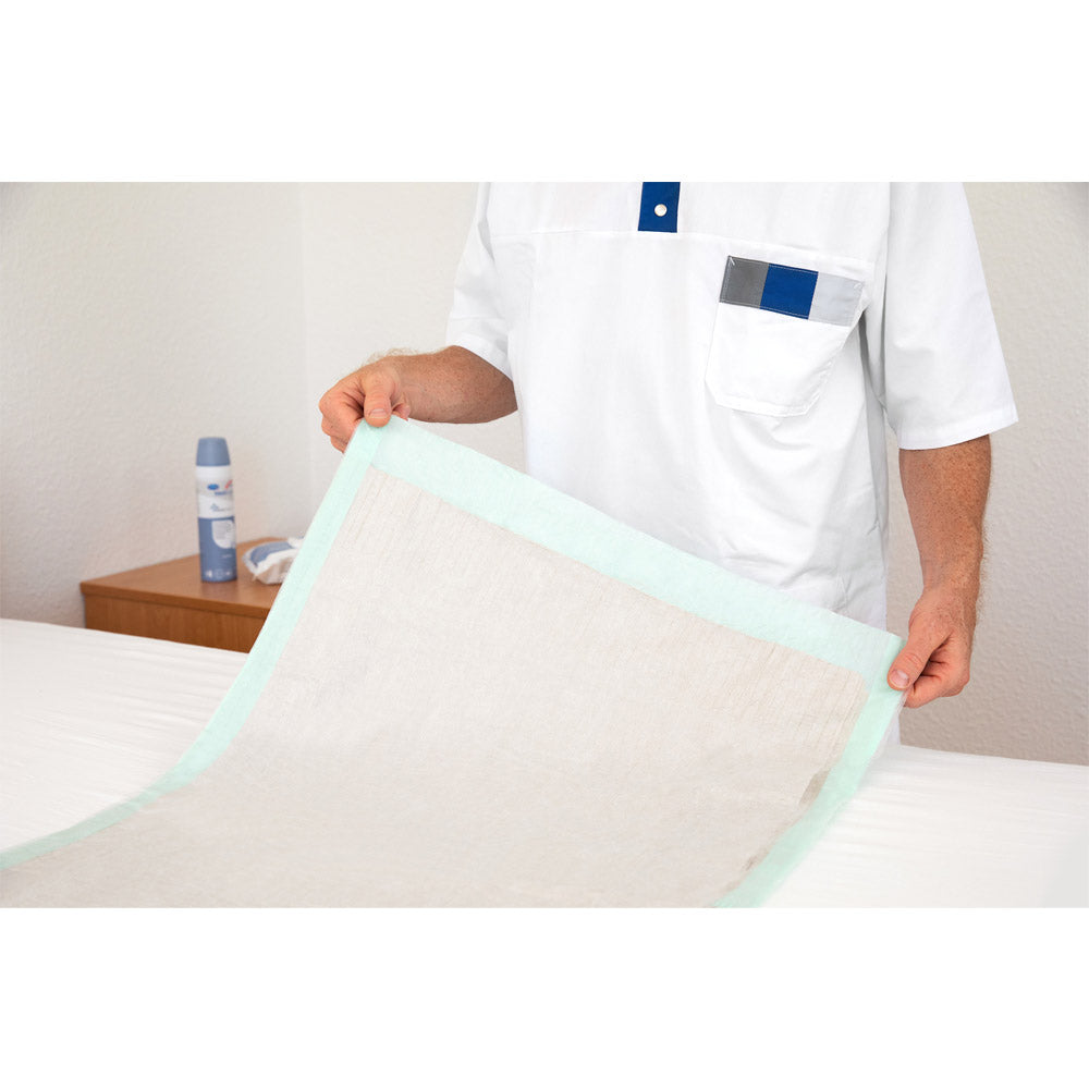 Inkontinenzunterlage Hartmann MoliCare® Bed Mat Eco auf dem Bett, hellbeige mit türkisfarbenem Rand