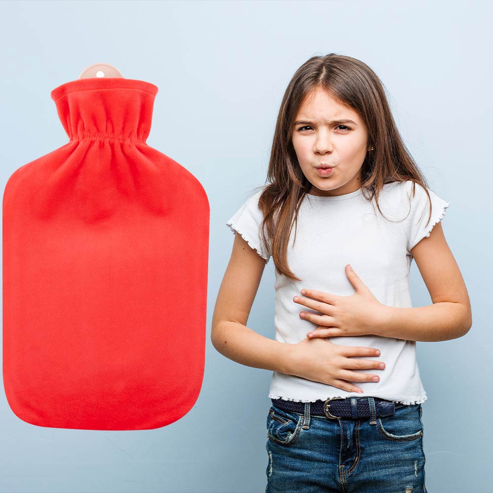 2‑Liter‑Wärmflasche in Koralle mit Flauschbezug, von einer Person am Bauch gehalten
