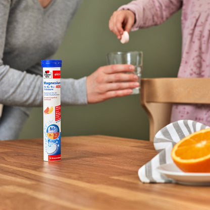 Doppelherz aktiv Magnesium 400 Brausetabletten-Röhrchen neben einem Glas