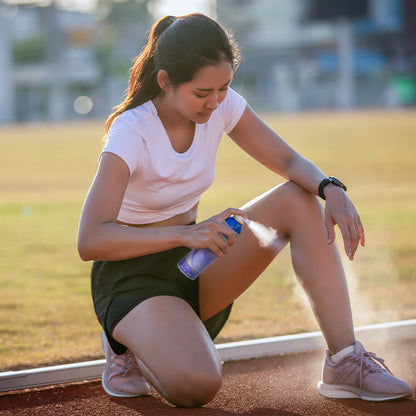 Kältespray-Spraydose in der Hand, wird auf das Knie einer Sportlerin gesprüht
