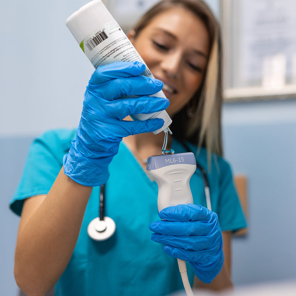 Ultraschallgel-Flasche in der Hand, blauer Handschuh mit Ultraschallsonde