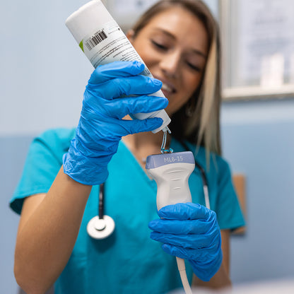 Ultraschallgel-Flasche in der Hand, blauer Handschuh mit Ultraschallsonde