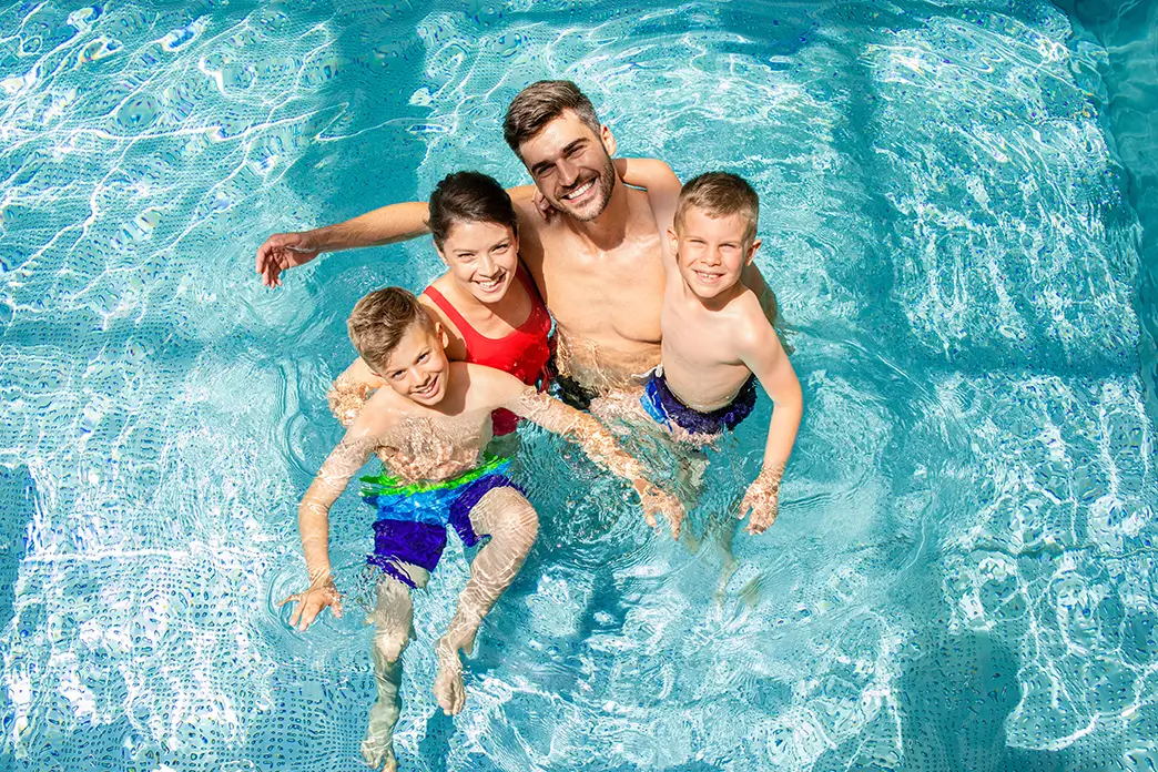 Eine vierköpfige Familie kühlt sich in einem Swimmingpool ab